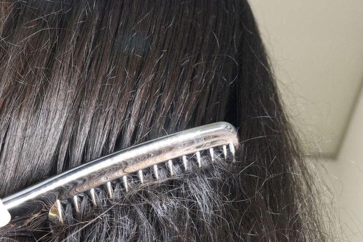 女性の黒髪をスムースコームでゆっくりと梳かしている様子