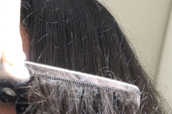 女性の黒髪をリファのコームでゆっくりと梳かしている様子
