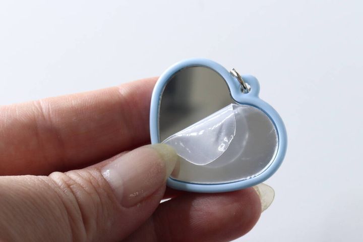 ハート型ミラーの表面保護フィルムを指で剥がしている様子