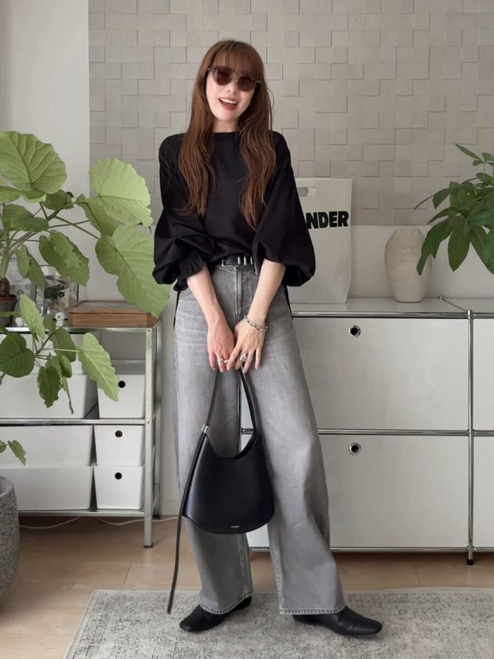 黒のボリューム袖ブラウスとグレーのストレートデニムを着用した女性