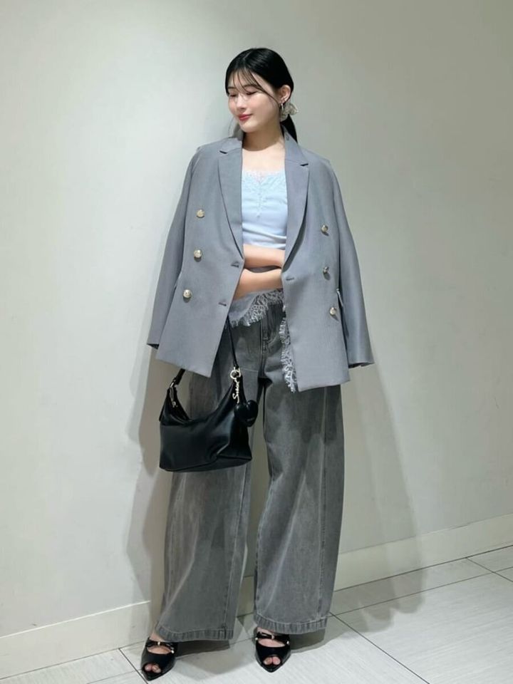 グレーのテーラードジャケットとワイドデニムを着用した女性