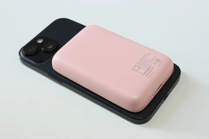 ピンクのモバイルバッテリーを黒いスマートフォンに重ねて充電している