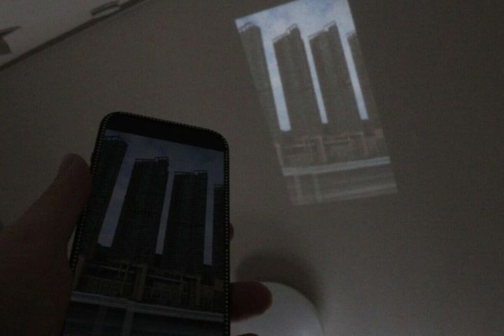 スマートフォンから壁に高層ビル群の映像を投影している