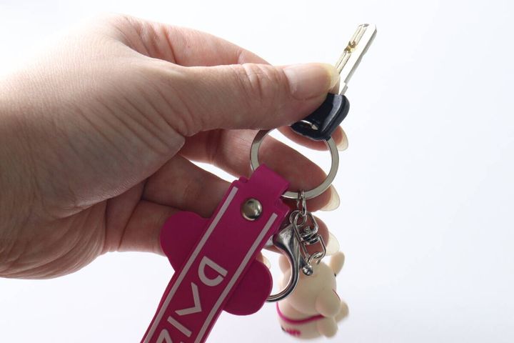 女性の手が持つキーホルダーに鍵が取り付けられている様子
