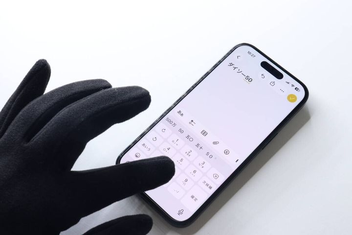 黒い手袋を着用した手がスマートフォンを操作している様子