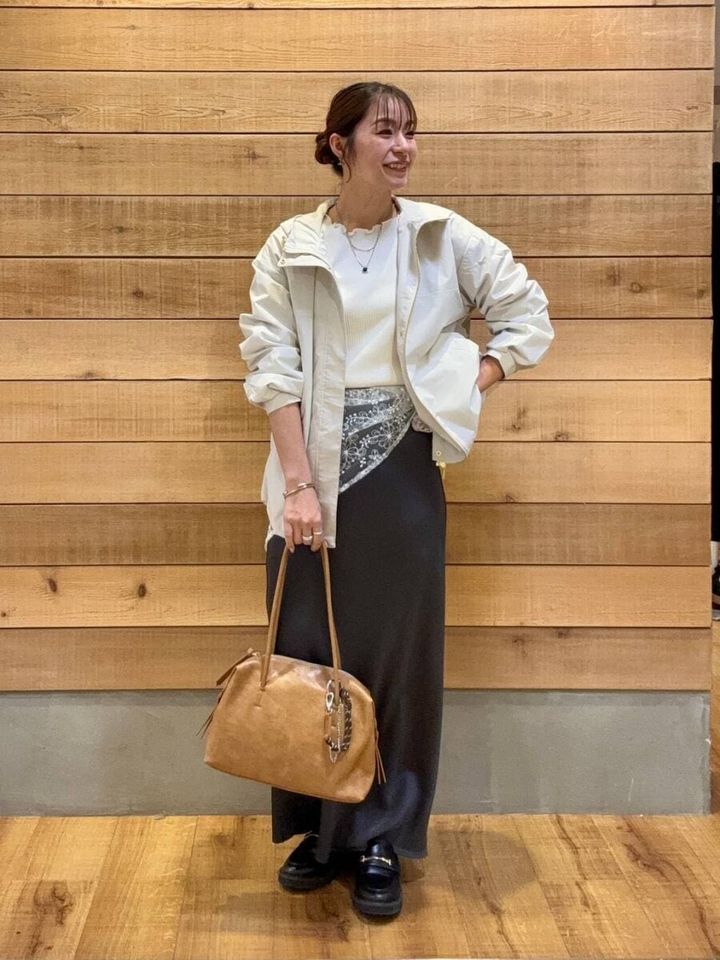 白いマウンテンパーカーと黒いロングスカートの女性