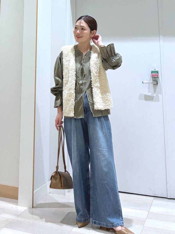 白いファーベストとデニムワイドパンツの女性