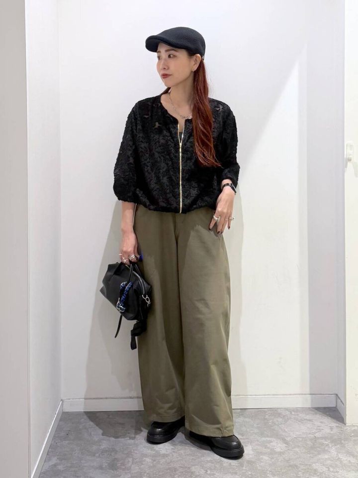 黒いジャガードブルゾンとカーキのワイドパンツを着た女性