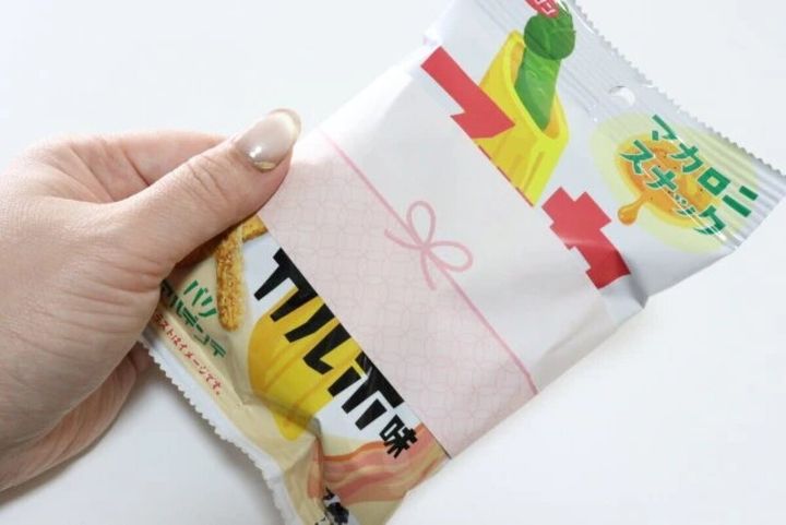 女性がスナック菓子にピンクののし風シールを貼っている