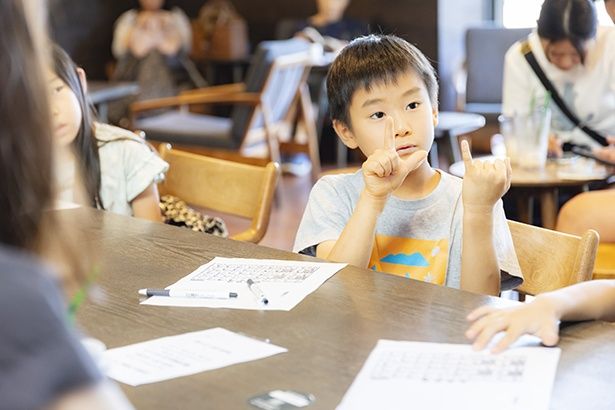 指文字で名前を伝える小学生