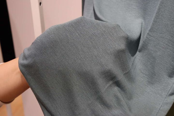 女性の手がユニクロタートルネックTの薄くしなやかな生地を広げている