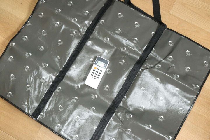 広げたバッグの上にエアコンのリモコンを置きサイズを比較
