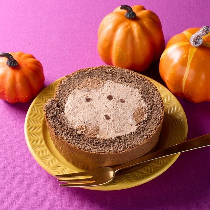紫の背景にハロウィンロールケーキとカボチャの飾り