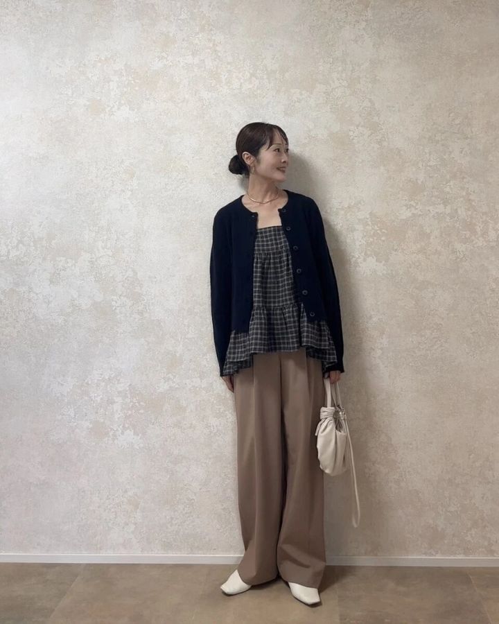 チュニックとベージュパンツに黒カーディガンを羽織った女性