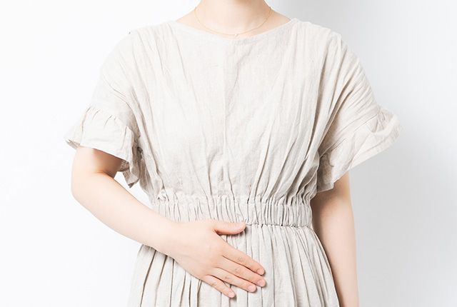 お腹に手を当てる若い女性