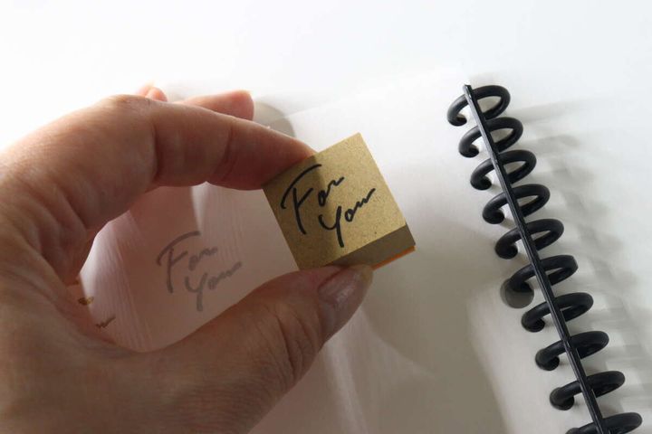 女性の手が「For You」のスタンプをノートに押している