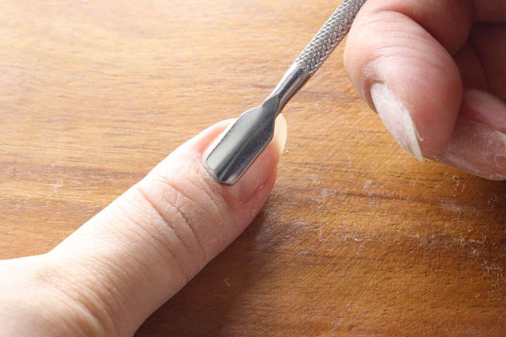 指の爪の甘皮をメタルプッシャーの幅広部分で押し上げている様子