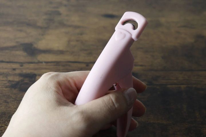 女性の手がピンク色のネイルクリッパーを握っている様子
