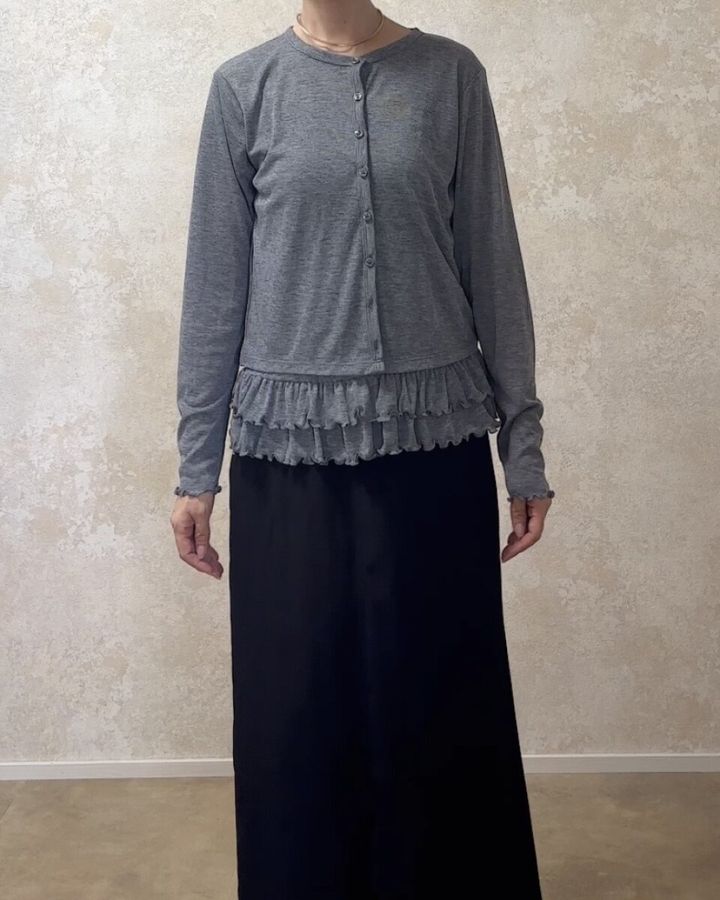 グレーのカーディガンと黒のロングスカートを着用した女性の全身