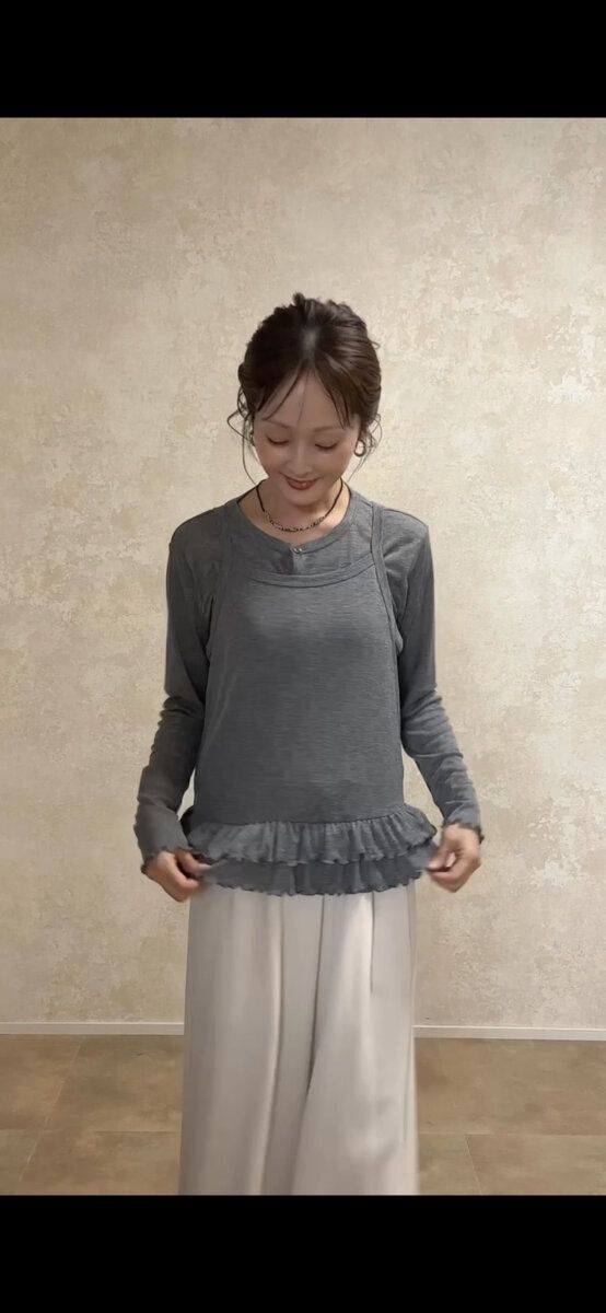 グレーのキャミソールとアイボリーのワイドパンツを着用した女性