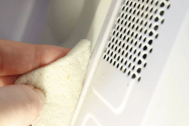 白いセスキクリーナーで電子レンジの庫内を拭く手元