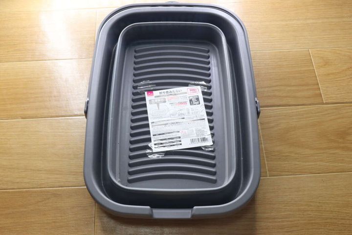 折り畳まれた状態のグレーのたらい。中央に商品ラベルが貼られている。