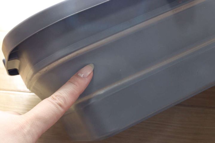 女性の指がたらいの側面を押し、素材の柔らかさや折り畳みやすさを示している。