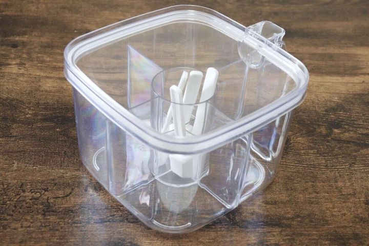 透明な4仕切り調味料ポット。中央に白い計量スプーンが収納されている。