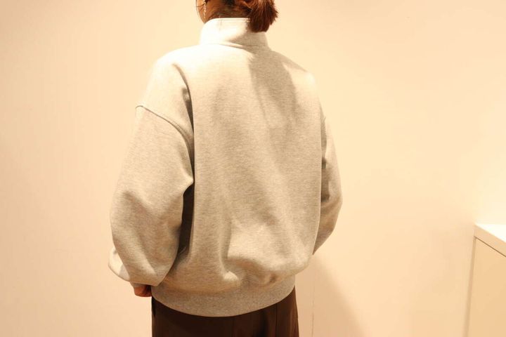グレーのハーフジップスウェットを着た女性の後ろ姿