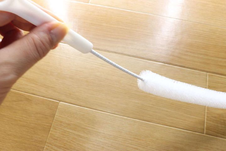 女性の手がパイプクリーナーのブラシ部分をしならせている
