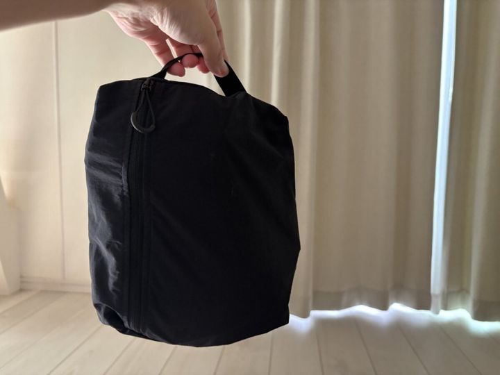 コンパクトにたたまれた黒いボストンバッグを手に持っている
