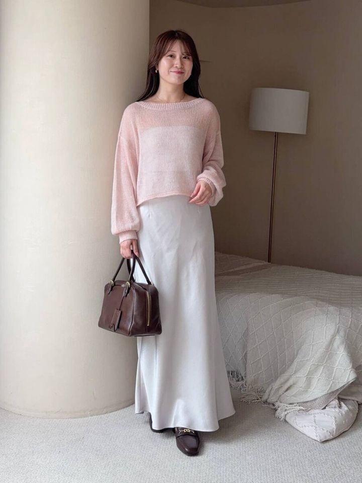 ピンクニットと白サテンスカートの女性