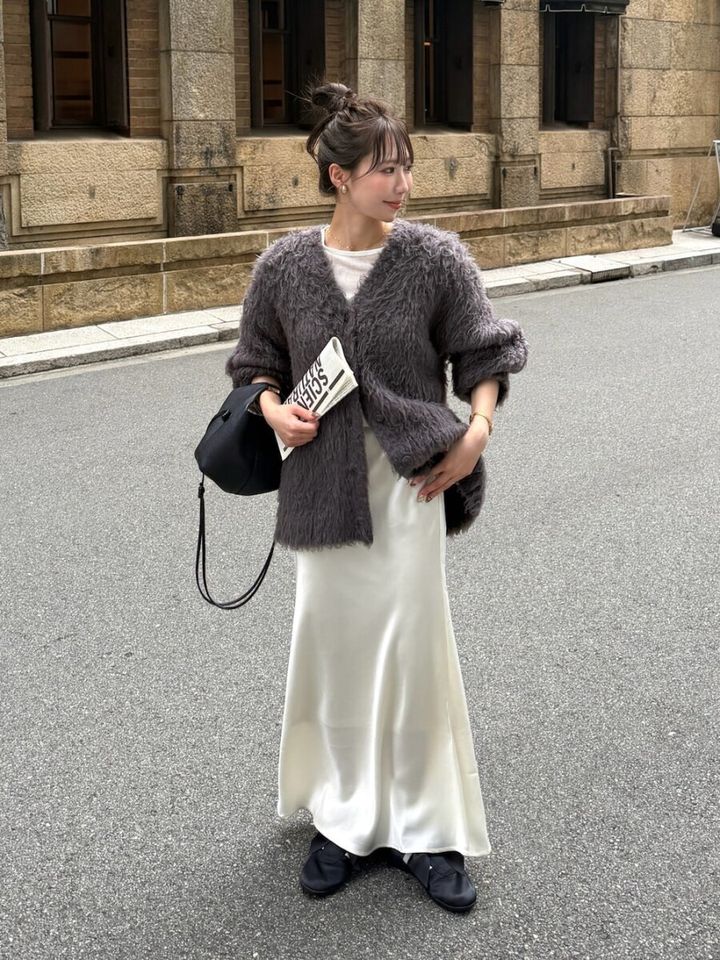 シャギーニットと白サテンスカートの女性