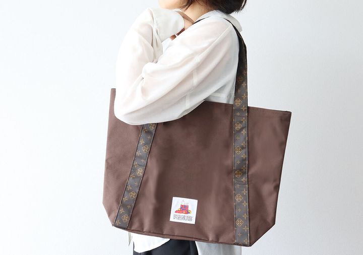 白シャツの女性がブラウンのショッピングバッグを肩にかけている
