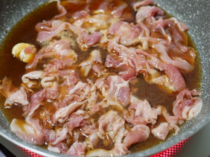 煮汁が入ったフライパンに豚こま切れ肉が加えられ、ほぐされている様子