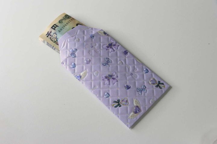 完成した紫色のデザインペーパーのポチ袋に千円札が入っている様子