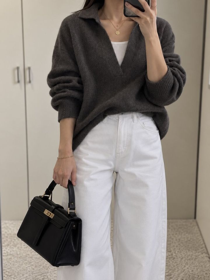 濃いグレーのニットと白パンツで自撮りする女性