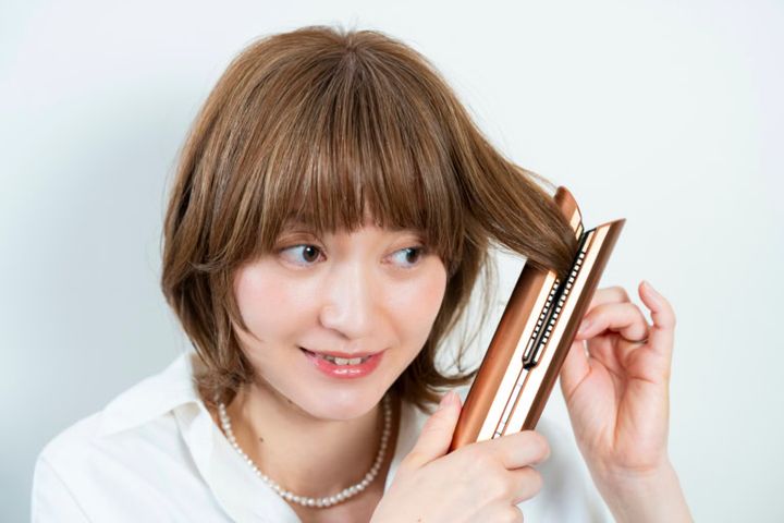 ヘアアイロンで顔まわりや表面の毛を内巻きに、毛先は外ハネに