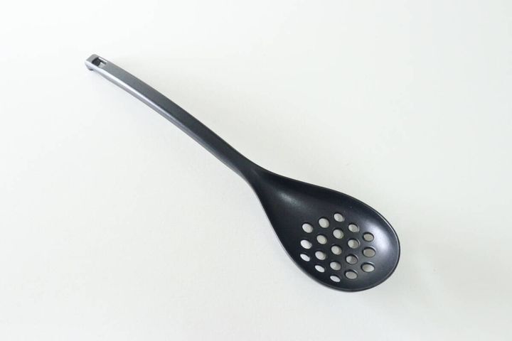 黒い穴あきレンゲが白い背景に置かれている