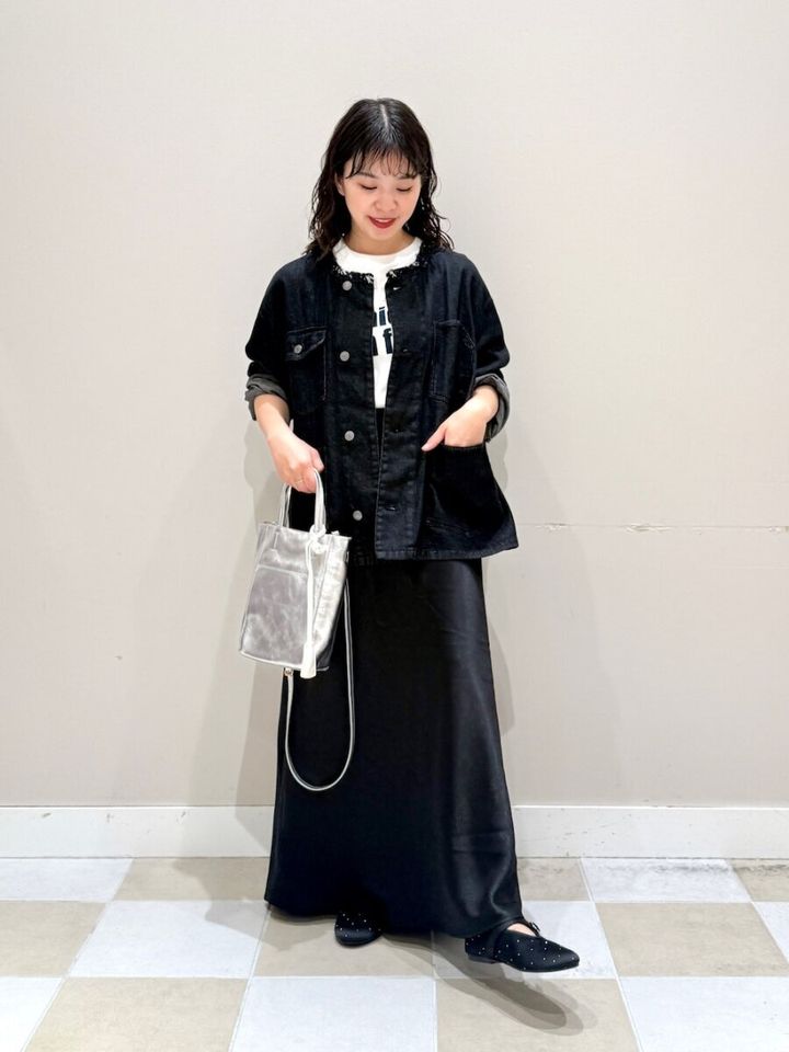 黒いフリンジGジャンと黒サテンスカートを着た女性