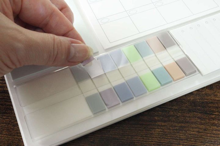 女性の指がカラフルなインデックスふせんを剥がしている