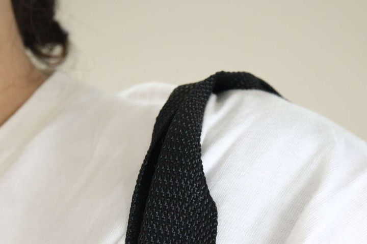 白いTシャツを着た人が、黒いアルミトートバッグを肩に掛けている