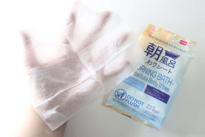 手のひらに広げた半透明のボディシートと、その奥にパッケージが見える