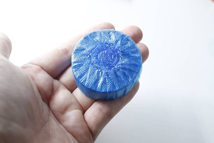 手のひらに乗せられたセリアの青いトイレ用防汚芳香洗浄剤