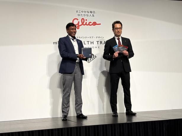 新サービス「mRNA HEALTH TRACKER」の検査キットを手に撮影に応じるジェインさん(左)と、江崎社長(右) 【撮影＝西脇章太】