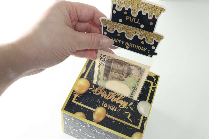 ケーキ部分を引っ張ると1万円札が出てくる様子