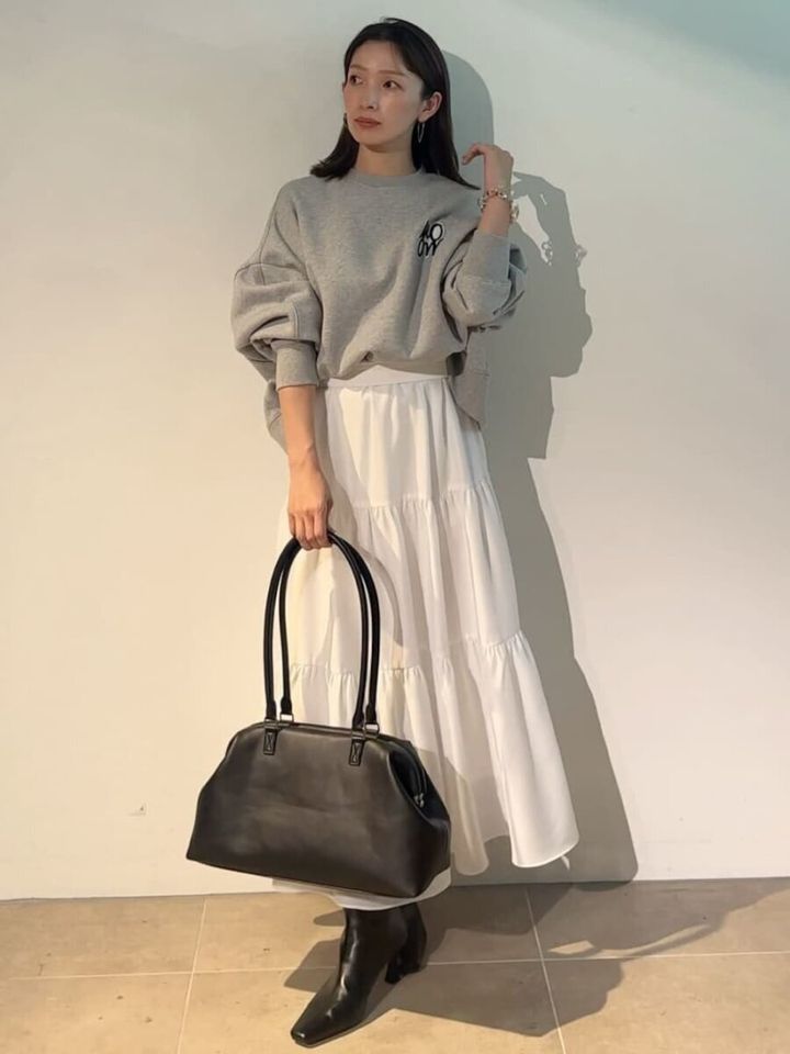 グレースウェットとティアードスカート姿で黒バッグを持つ女性