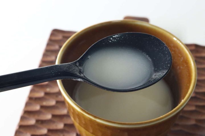 茶色のカップに入ったポタージュスープを、黒いスプーンですくっている様子