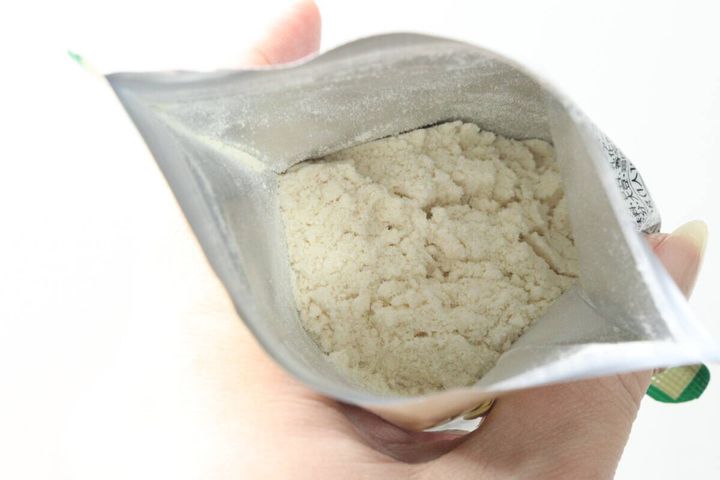 パッケージを開けて中身のポタージュ粉末を見せている手元