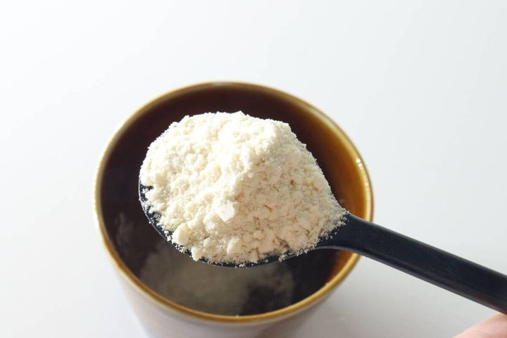 茶色のカップの上で、山盛りのポタージュ粉末をすくった黒いスプーン